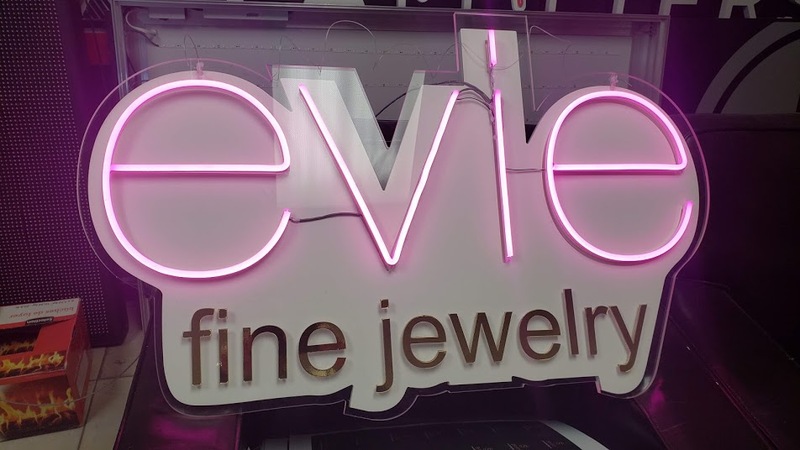 Custom neon logo sign for a jewelry store  -  elegant script neon lettering on black acrylic backing, warm amber colour